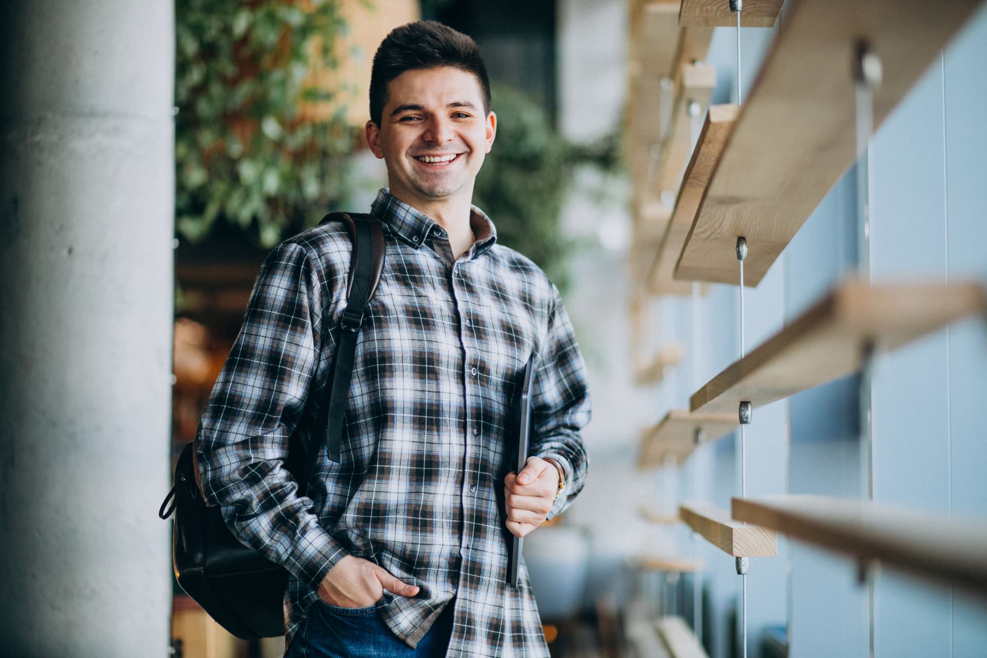 Jovem sorrindo com notebook em ambiente de estudo